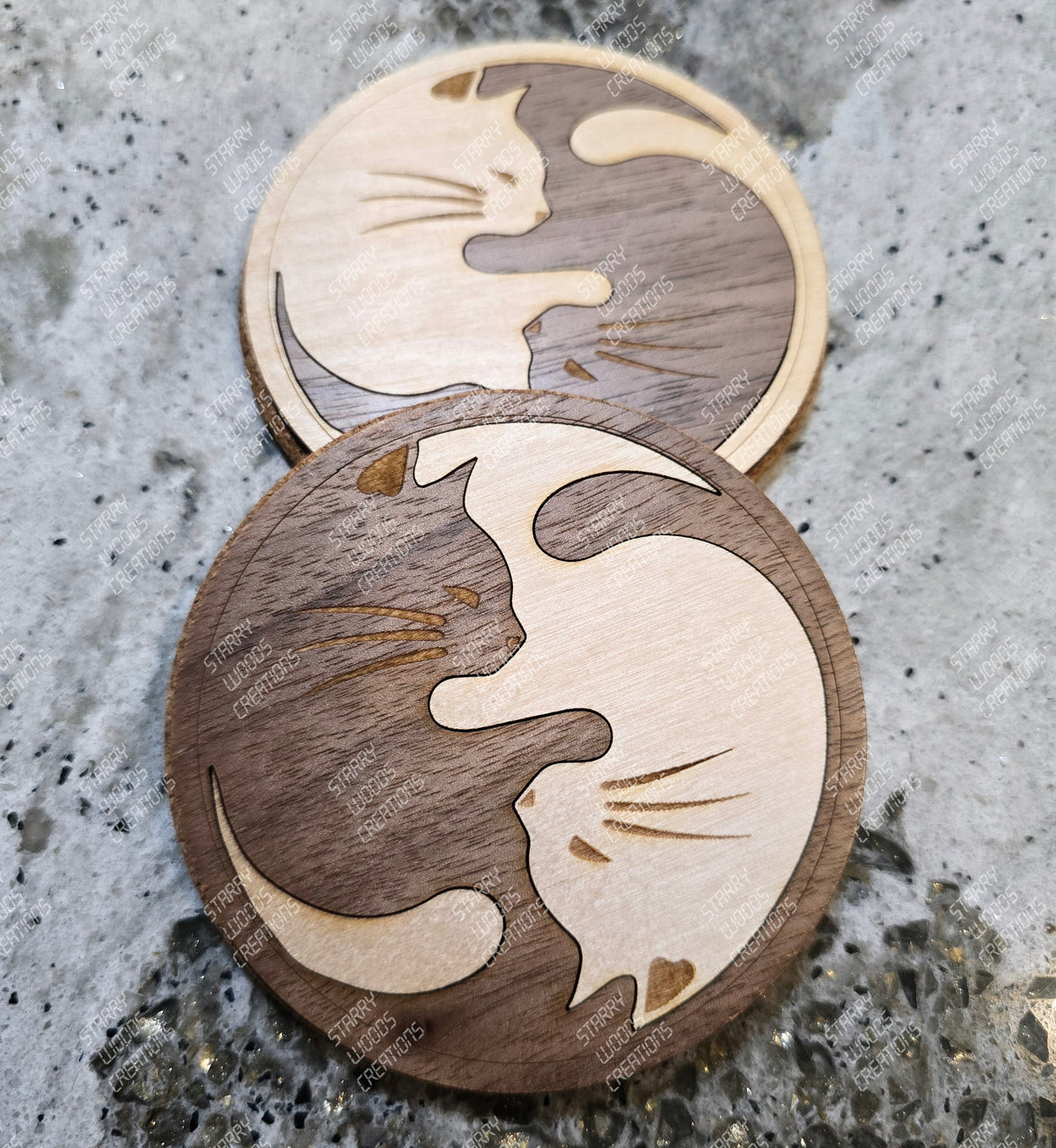 A set of round wooden coasters with a cork backing, featuring cut-out cat shapes in a yin-yang design. Design is a mixture of walnut and birch creating contrast between the two cats.