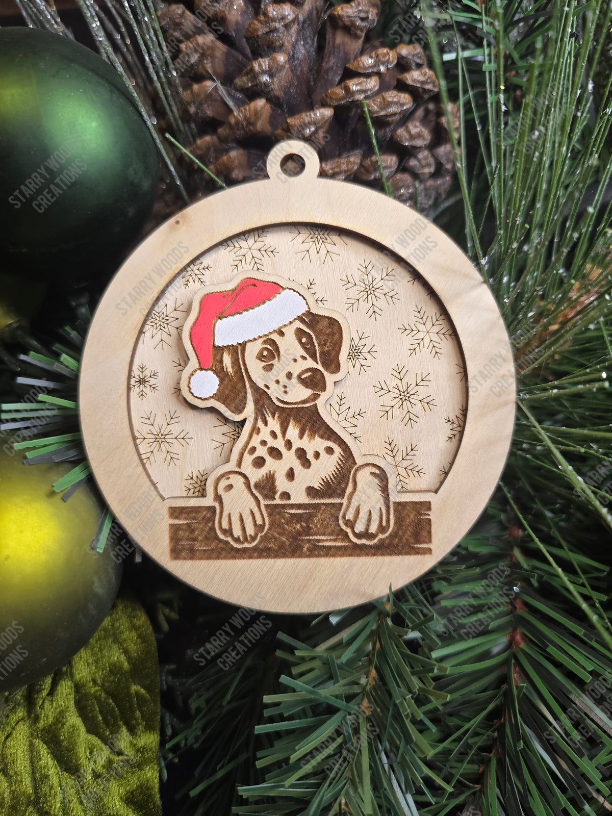 Wooden Christmas ornament with a dalmation wearing a Santa hat on a green pine branch.