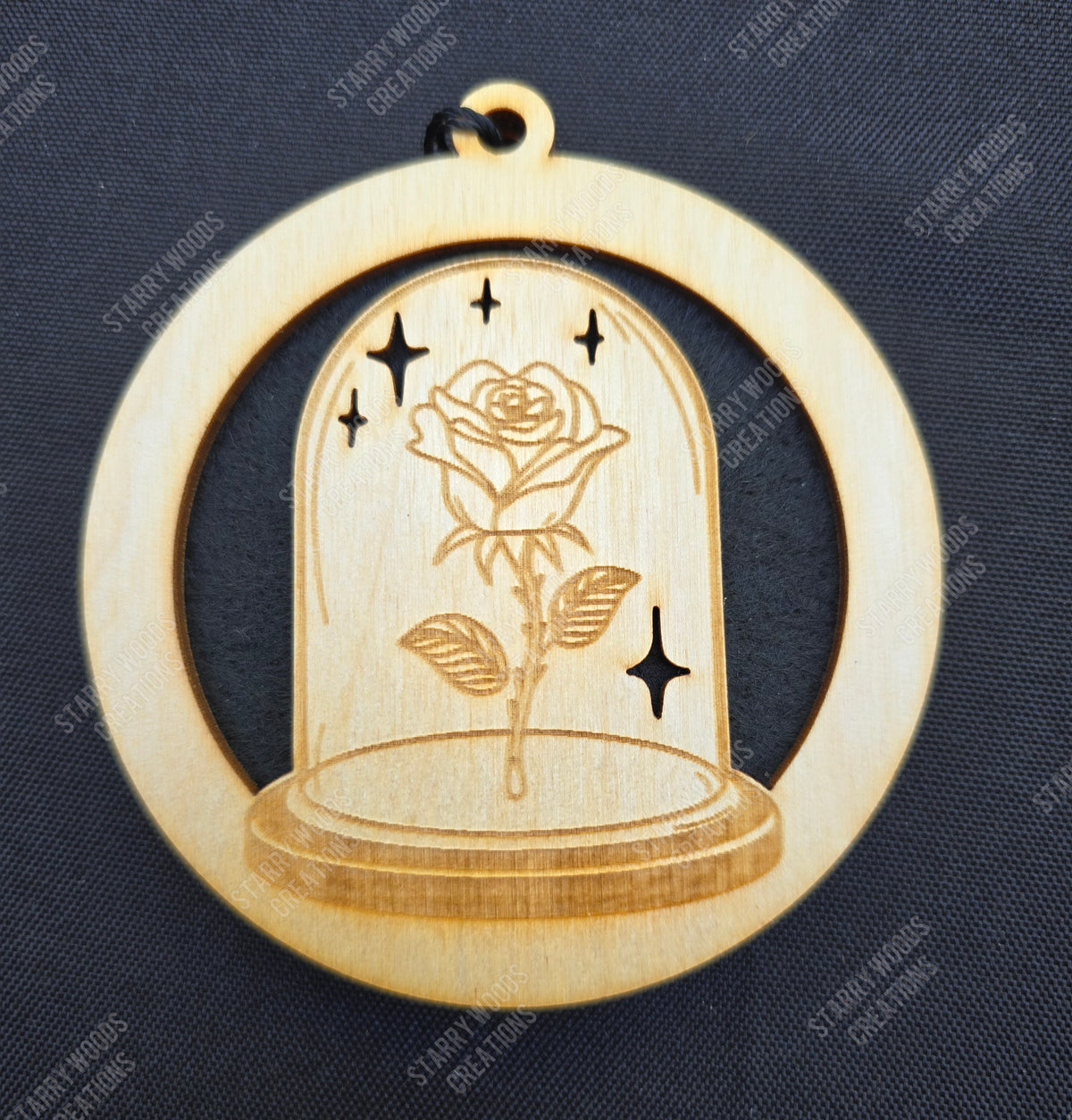 Wooden hanging air freshener with a rose design inside a glass dome on a dark blue background.