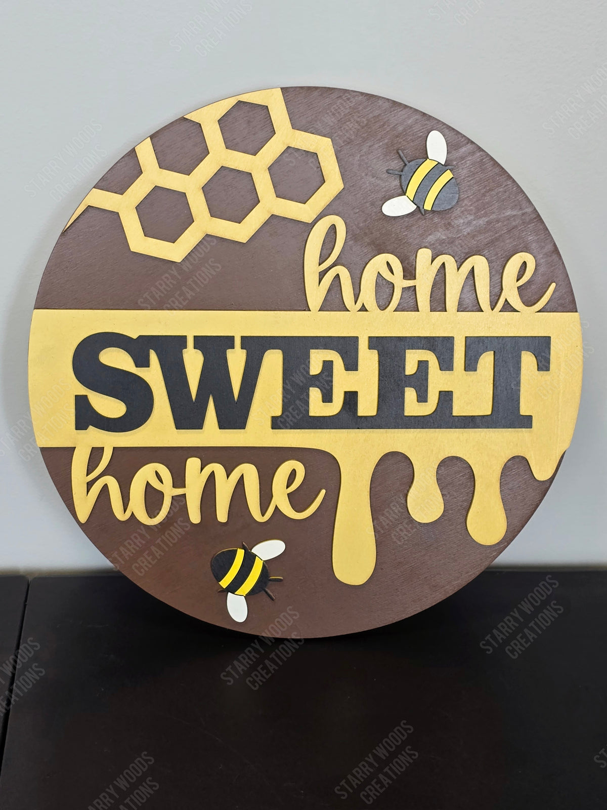 Decorative sign with 'home sweet home' text and honeycomb design on a brown background.