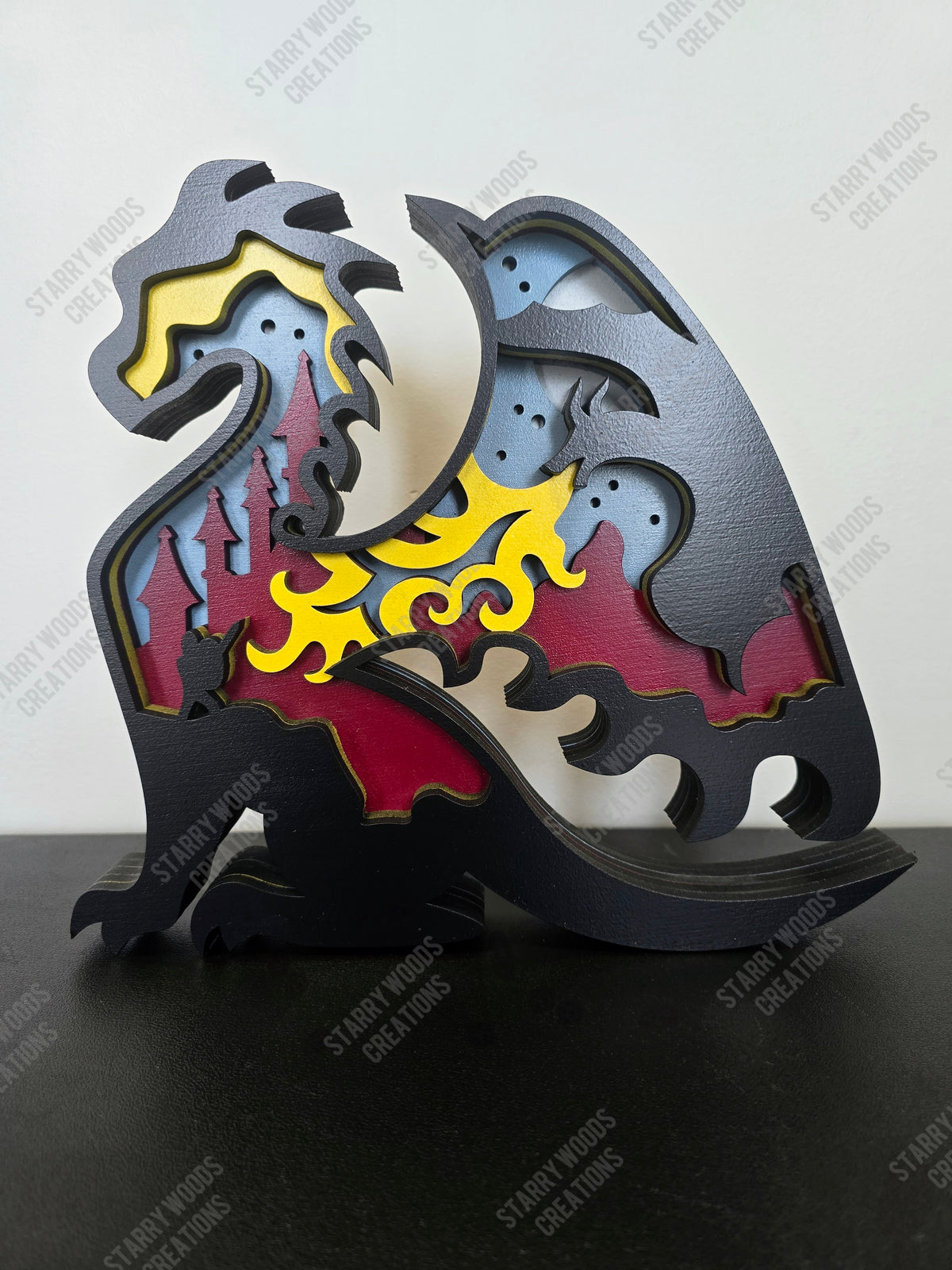 Decorative layered wood decor of a dragon with colorful design and knight inlay on a black surface. Can be used as a shelf sitter or wall art.