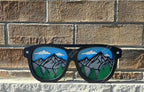 Layered wooden sunglasses with mountain and forest design on a brick wall background. 3D decor that works as a shelf sitter or wall art, handmade in Ontario.