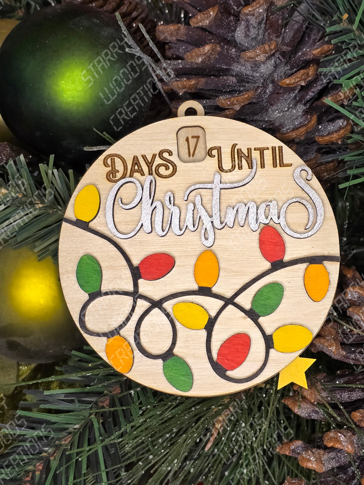A wooden Christmas countdown ornament with colorful numbered light designs and the text 'days until Christmas' in a circular arrangement, placed against a festive background with other ornaments.