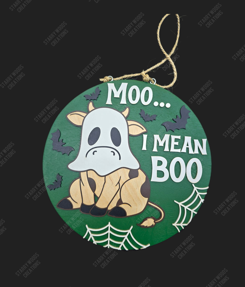 Halloween-themed round sign with a cow wearing a ghost costume and text 'Moo... I Mean Boo' on a green background.