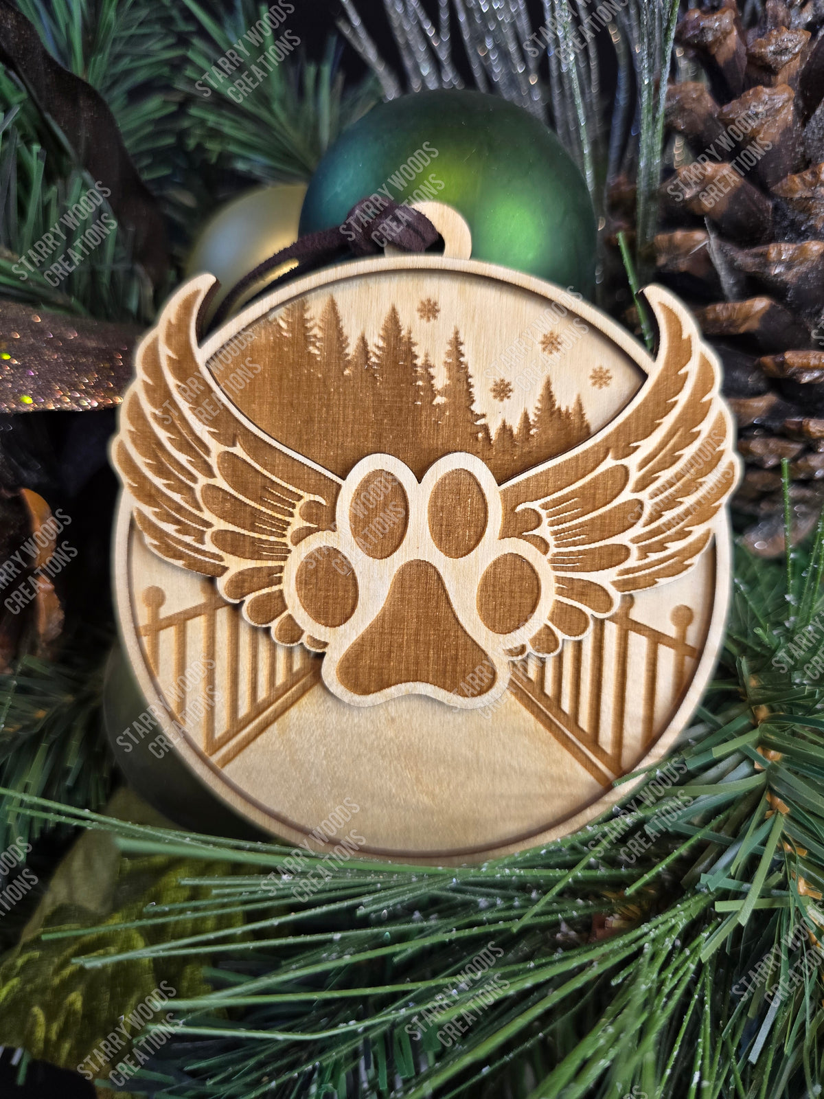 Decorative pet memorial ornament with paw print and wings design, with engraved rainbow bridge on a green pine branch. Bridge has space for customization.