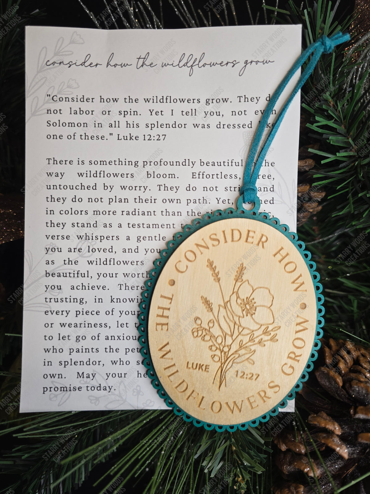 Decorative wooden ornament with engraved text referencing Luke 12:27 and floral design, placed on the included story card