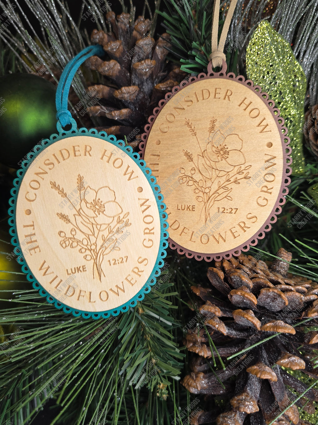 Two wooden ornaments with floral designs and engraved text referencing Luke 12:27 on a Christmas tree. Handmade in Quinte West and customizable